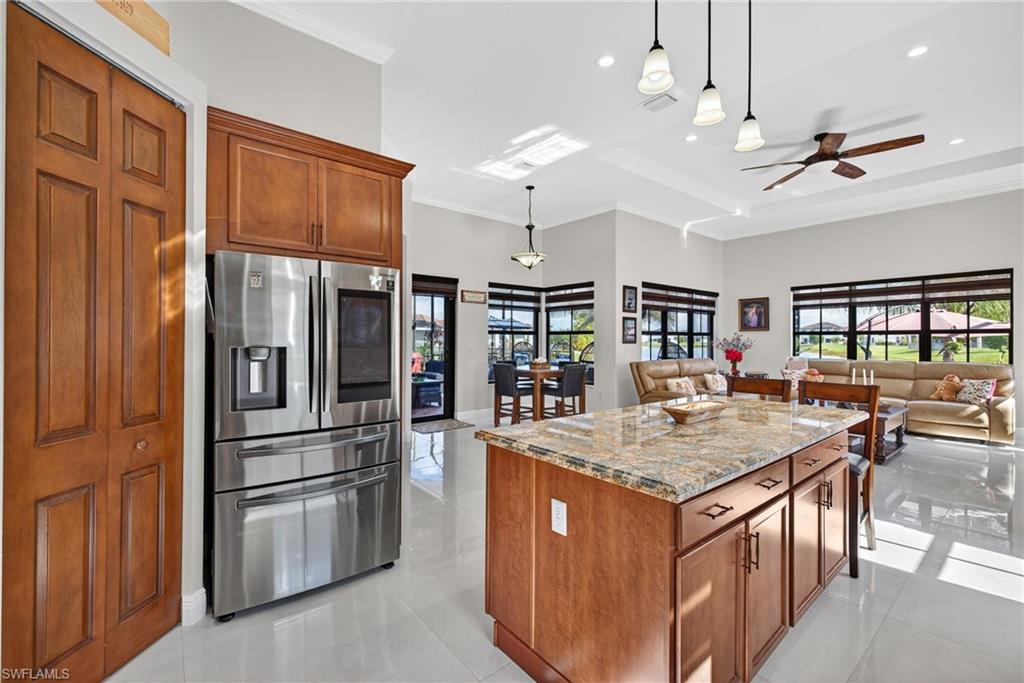 5102 Genoa Street Immokalee, FL 34142 - Photo 6 of 36 a kitchen with stainless steel appliances granite countertop a refrigerator a stove a kitchen island with chairs and wooden floor