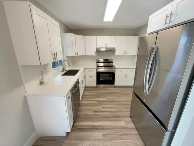 a kitchen with a sink a refrigerator a stove and white cabinets