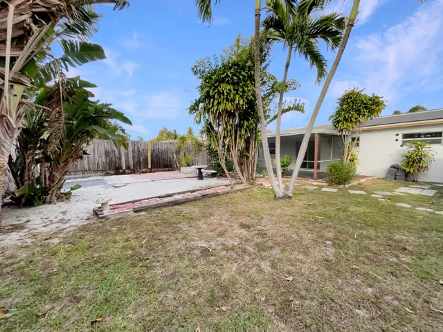 a view of a house with a yard and palm trees