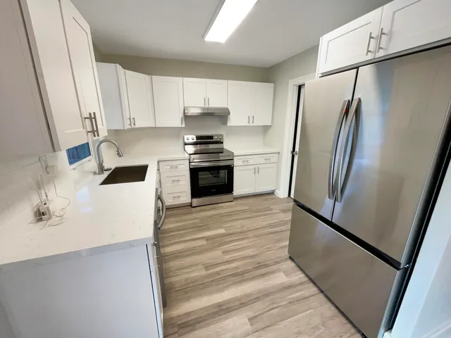 a kitchen with stainless steel appliances a refrigerator sink and white cabinets