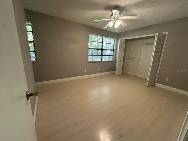 an empty room with windows and ceiling fan