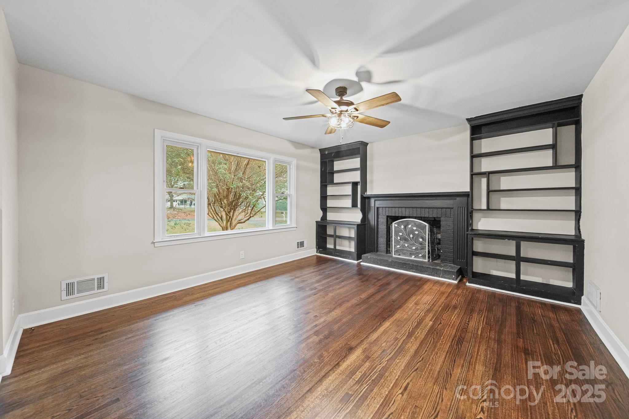 1331 Stegall Road Marshville, NC 28103 - Photo 2 of 35 an empty room with windows fireplace and wooden floor