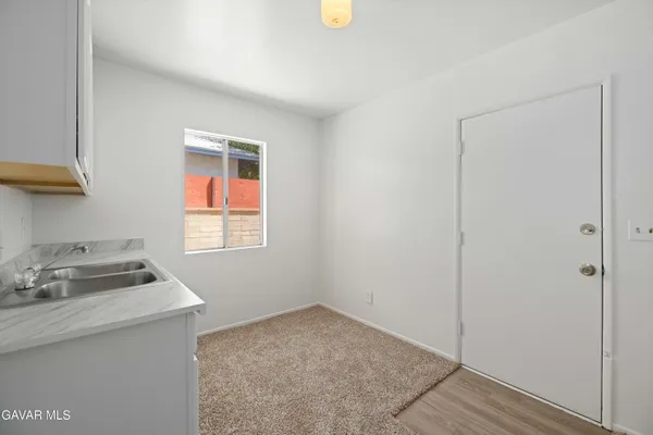a view of an empty room with a window and a kitchen
