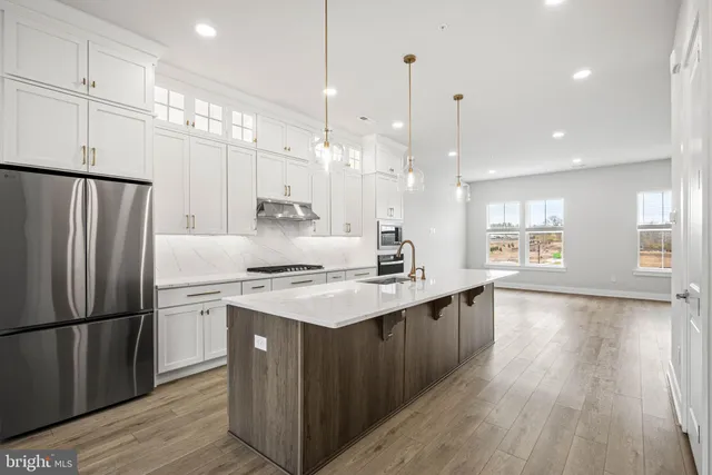 a kitchen with a refrigerator a stove and a sink with wooden floor