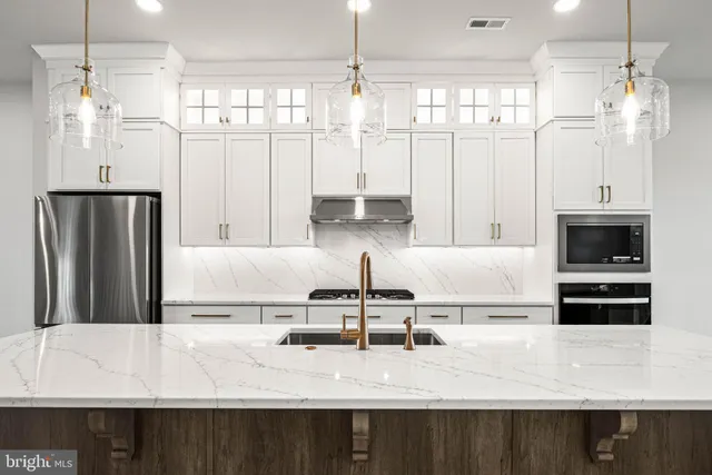 a large kitchen with stainless steel appliances a large center island attached withe living room