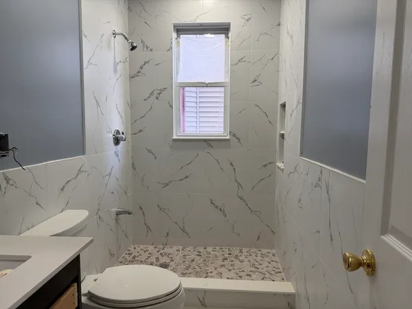 a bathroom with a sink a toilet and shower