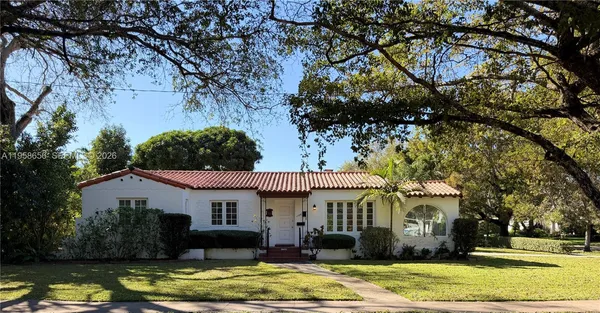 a front view of a house with a garden and tree