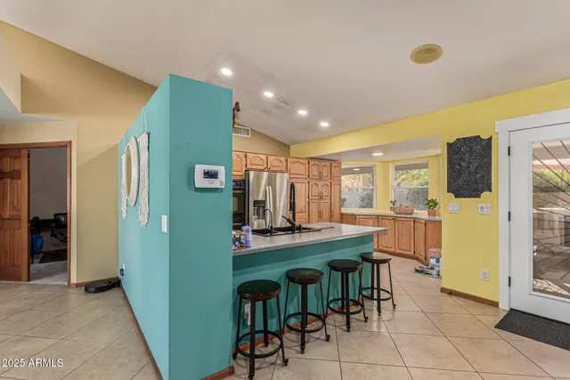 a kitchen with stainless steel appliances granite countertop a refrigerator a stove a sink and a dining table with white cabinets