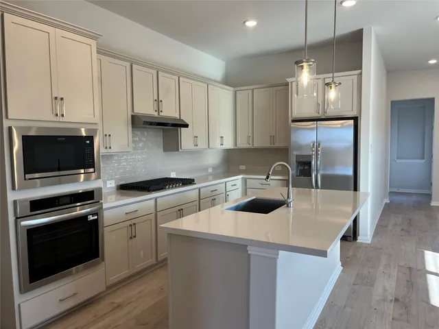 a kitchen with stainless steel appliances granite countertop a sink a stove and a refrigerator