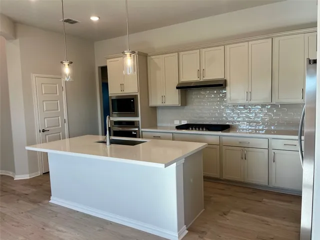 a kitchen with kitchen island granite countertop a sink and a stove top oven