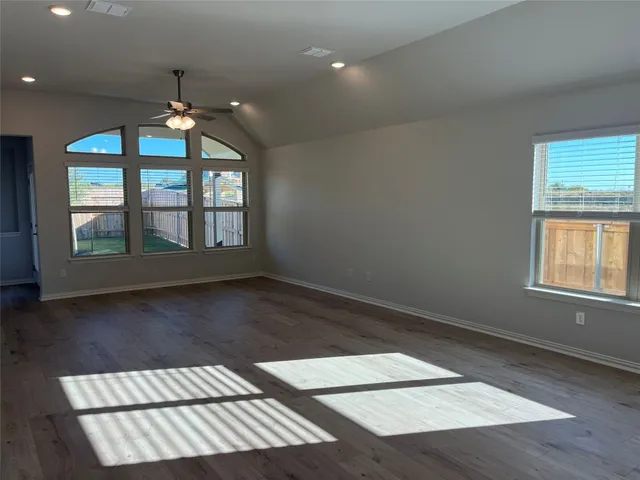 an empty room with wooden floor chandelier and windows