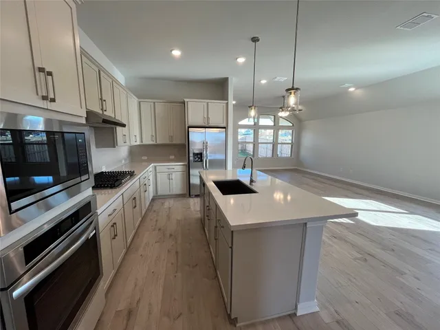 a kitchen with a sink a counter top space stainless steel appliances and cabinets