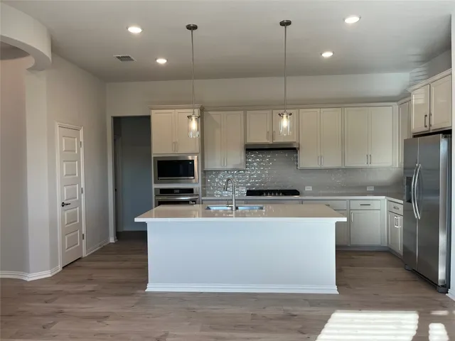 a kitchen with kitchen island a sink stainless steel appliances and cabinets