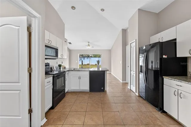 a view of living room with stainless steel appliances kitchen island a sink a refrigerator and cabinets