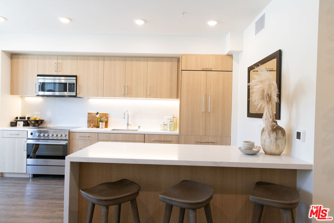 7566 West Sunset Boulevard, Unit 411PHE Los Angeles, CA 90046 - Photo 3 of 15 a kitchen with a table chairs stove and cabinets