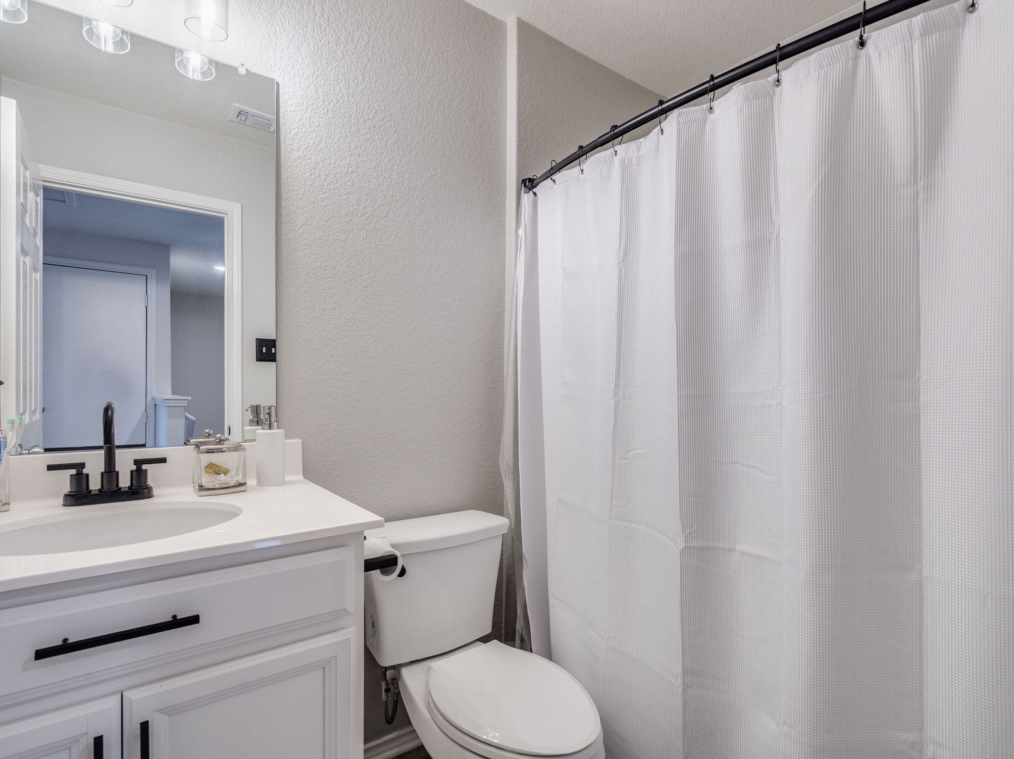624 Pepperbark Loop Buda, TX 78610 - Photo 20 of 32 a bathroom with a sink a toilet a mirror and shower curtain