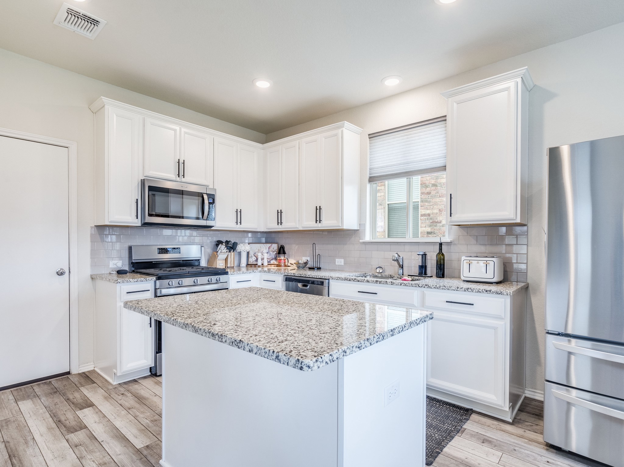 624 Pepperbark Loop Buda, TX 78610 - Photo 9 of 32 a kitchen with a sink a refrigerator a microwave and cabinets