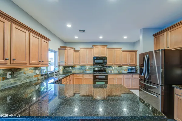 a large kitchen with stainless steel appliances granite countertop lots of counter top space and wooden floor