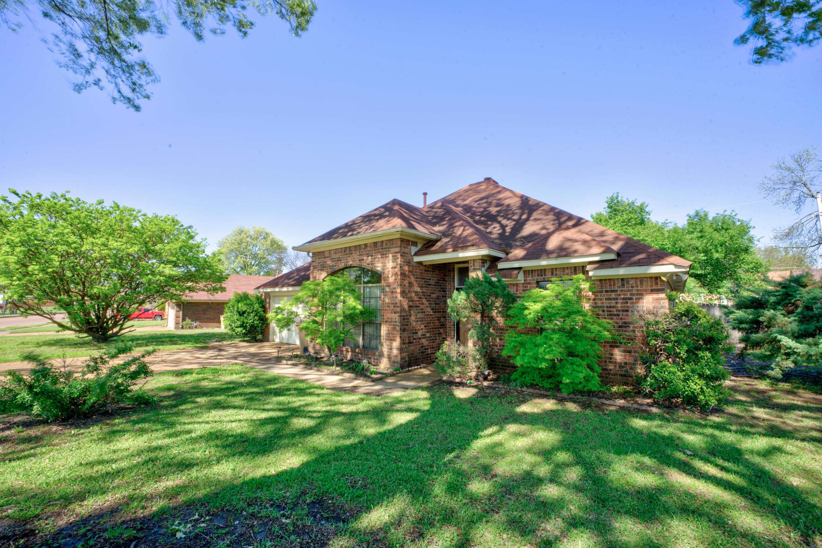 View of front of home with roof with shingles, a front yard, brick siding, and an attached garage