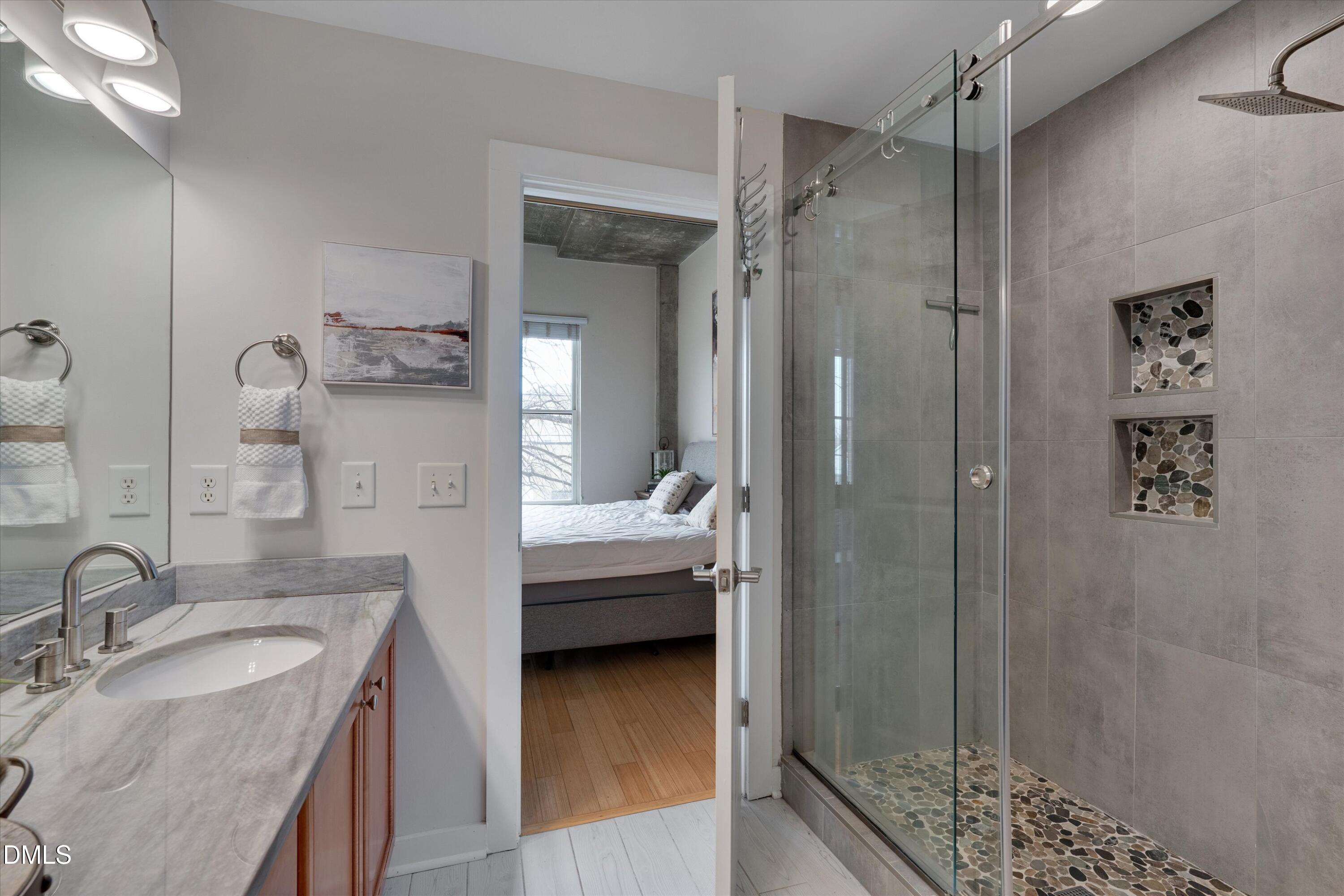 444 South Blount Street, Unit 120 Raleigh, NC 27601 - Photo 10 of 29 a en suite bathroom with a granite countertop sink mirror and shower