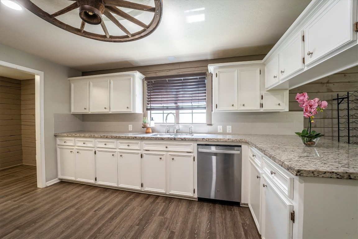12049 Clark Lane Conroe, TX 77385 - Photo 11 of 40 a kitchen with stainless steel appliances granite countertop a sink and dishwasher a stove top oven with wooden floor