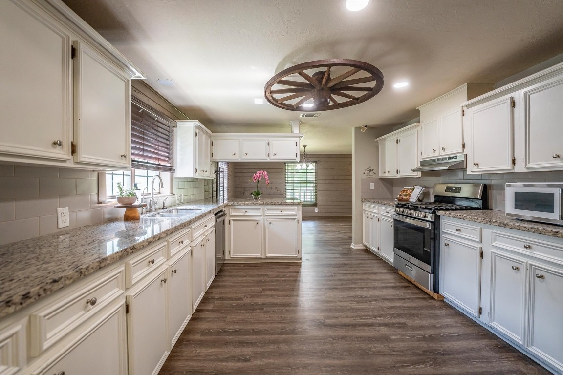 12049 Clark Lane Conroe, TX 77385 - Photo 13 of 40 a large kitchen with stainless steel appliances granite countertop a large stove a sink and dishwasher a oven with white cabinets