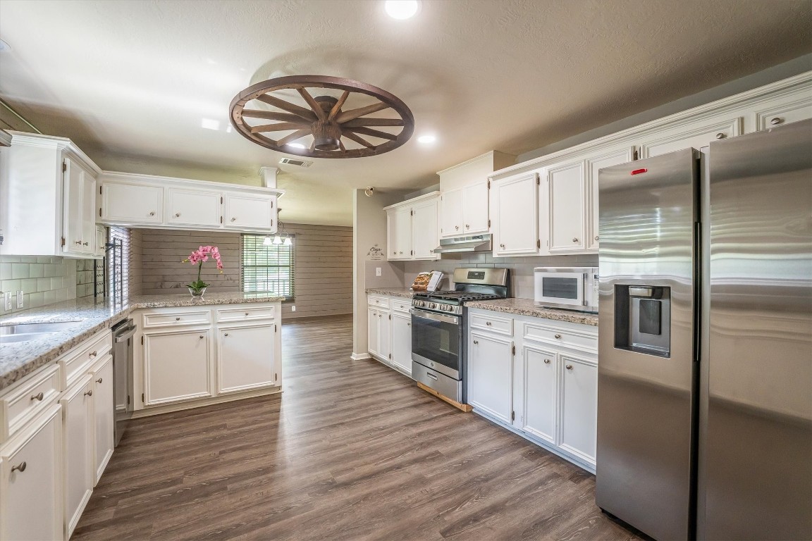 12049 Clark Lane Conroe, TX 77385 - Photo 14 of 40 a kitchen with granite countertop stainless steel appliances cabinets a sink and a large window