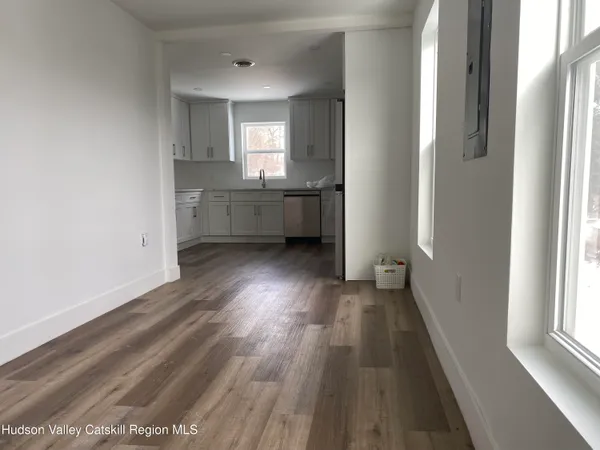 a view of an empty room with a window and wooden floor