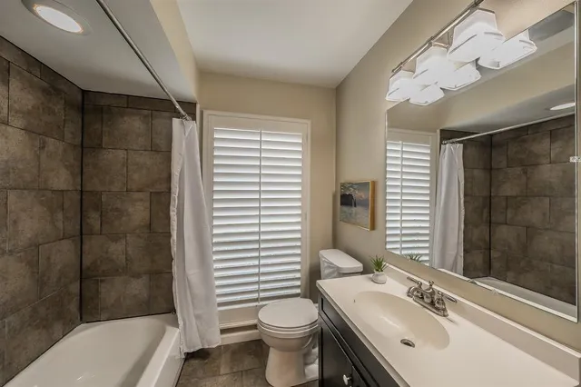 a bathroom with a sink a toilet a mirror and shower