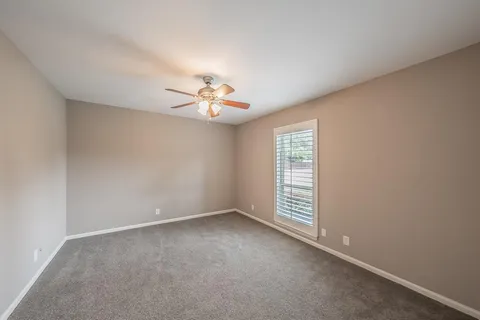 an empty room with windows and chandelier fan