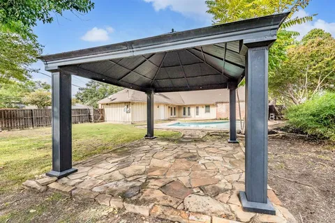a backyard of a house with table and chairs under an umbrella