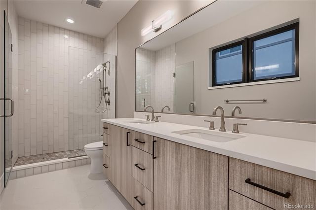 a bathroom with a double vanity sink toilet mirror and shower