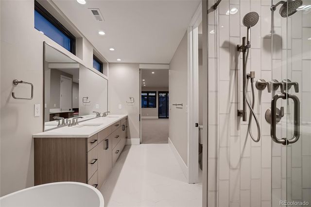 a spacious bathroom with a double vanity sink a toilet a mirror and shower