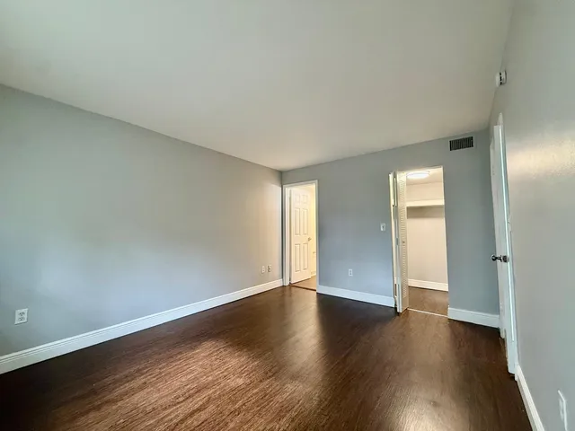 a view of an empty room with wooden floor and closet