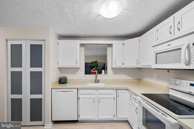 a kitchen with white cabinets and white appliances