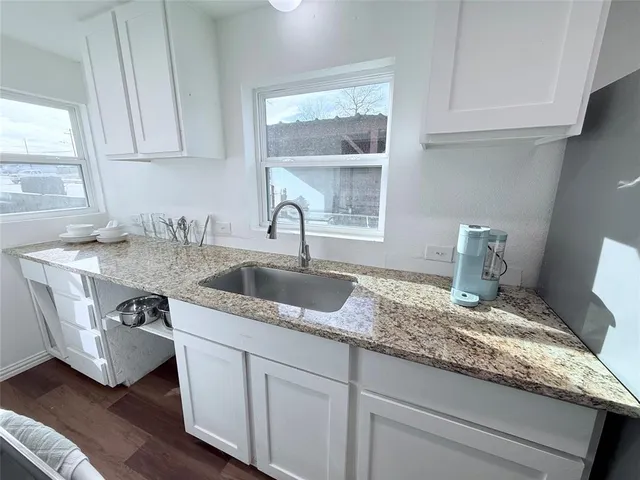 a kitchen with granite countertop a sink a stove and cabinets