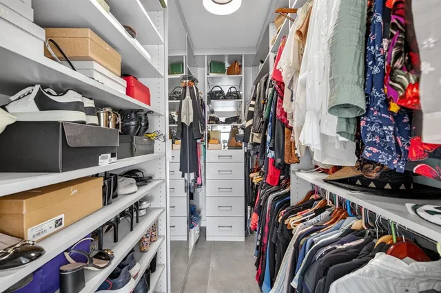 a view of walk in closet with clothes and shoes