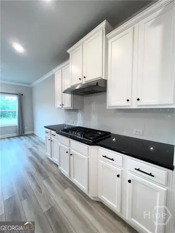 a kitchen with granite countertop white cabinets and a stove