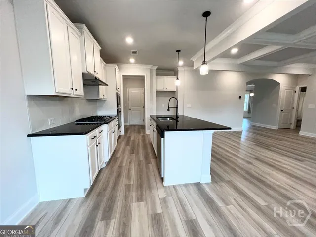 a kitchen with stainless steel appliances a refrigerator a sink dishwasher a stove and white countertops with wooden floor