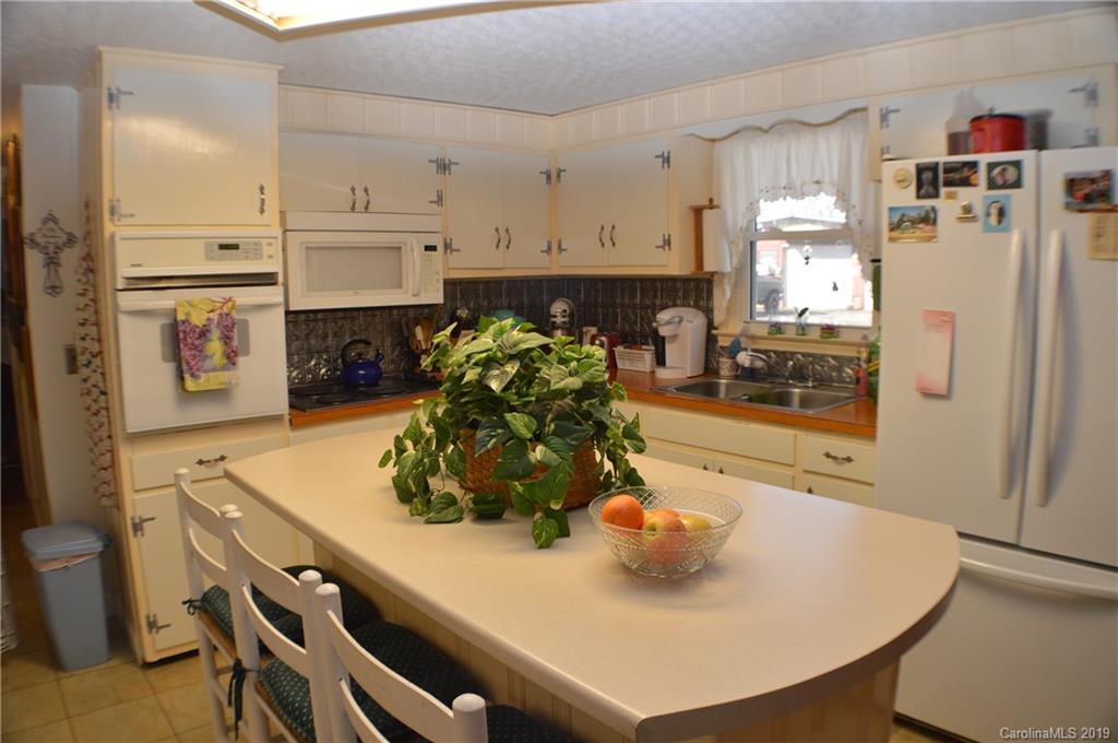 2395 Cove Road Rutherfordton, NC 28139 - Photo 7 of 25 a kitchen with stainless steel appliances a refrigerator a sink a stove a dining table and chairs