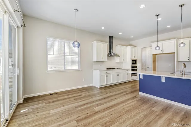 a large kitchen with kitchen island a stove a sink a center island and wooden floor