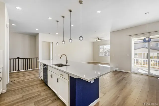 a open kitchen with kitchen island a stove a sink a center island and wooden floor