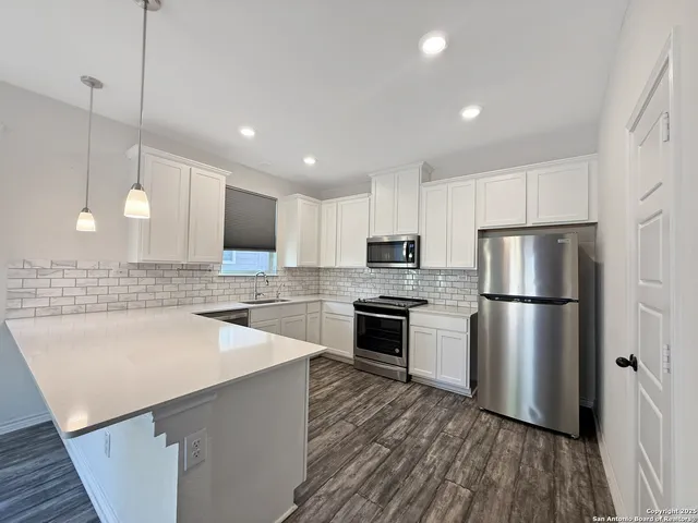 a kitchen with a refrigerator a sink and wooden floor