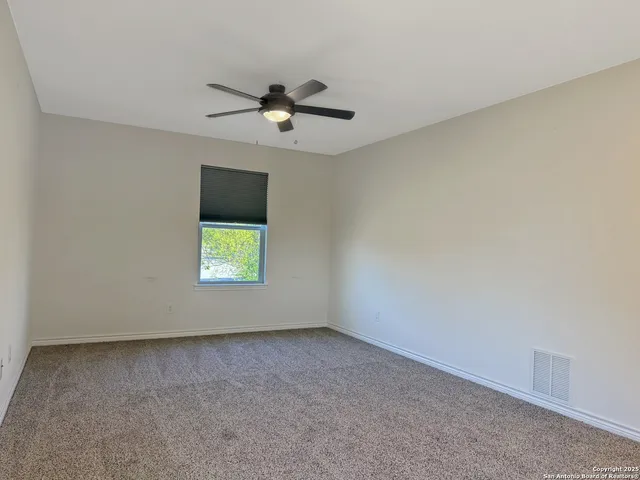 an empty room with a window and a ceiling fan