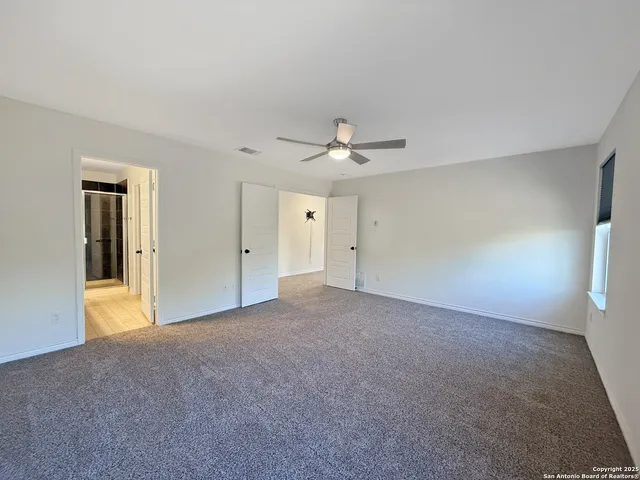 a view of a livingroom with a chandelier fan and windows