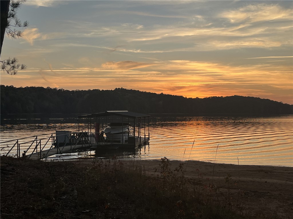 474 Overlook Drive Fair Play, SC 29643 - Photo 1 of 10 Golden hues paint the sky over a serene lake, featuring a private dock and boat slip.