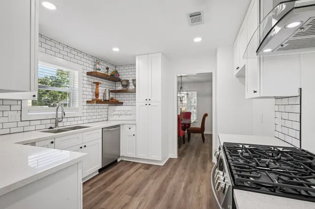 a kitchen with stainless steel appliances a stove a table and chairs