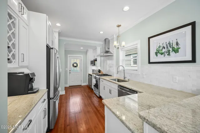 a large kitchen with stainless steel appliances granite countertop a lot of counter space and wooden floor
