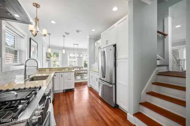 a kitchen with stainless steel appliances a refrigerator a stove a sink cabinets and wooden floor