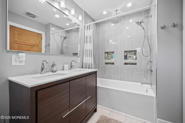 a bathroom with a bathtub shower sink vanity and mirror